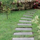 Une allée de jardin avec des lames en pierre reconstituée